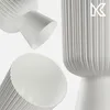 Three white ribbed vases are arranged against a white background. One vase is partially visible from the top, another is shown from the side, and the third is viewed from the bottom. Podgląd zdjęcia produktu
