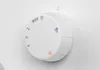 A close-up of a white rotary dial with markings and numbers on a white surface. Produktbild-Vorschau