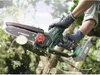 A person is using a cordless chainsaw to cut a tree branch outdoors. Produktbild-Vorschau