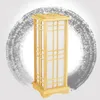A wooden lantern-style floor lamp with parchment panels, set against a grey brushstroke circle on a white background. Náhled obrázku produktu