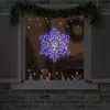 A snowflake-shaped light decoration hangs in a window, with Christmas decorations visible inside. Produktbild-Vorschau