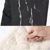 Nahaufnahme von schwarzem wasserdichtem Stoff mit abperlendem Wasser und einer Hand, die weiches beiges Fleecefutter berührt Produktbild-Vorschau