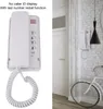 A split image showing a white wall-mounted phone on the left and the same phone installed on a white brick wall on the right, next to a bicycle and a pendant lamp. Podgląd zdjęcia produktu