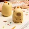 Two capybara-shaped night lights are placed on a desk next to a keyboard and some office supplies. Náhled obrázku produktu