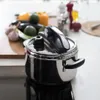 A pressure cooker is placed on a stovetop with vegetables and spices in the background. Anteprima dell’immagine prodotto