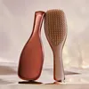 Two Tangle Teezer hairbrushes are displayed on a reflective surface with a soft, draped background. Anteprima dell’immagine prodotto