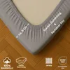 A close-up view of a fitted sheet corner on a bed, with icons and text highlighting product features. Produktbild-Vorschau