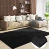 A living room scene featuring a sectional sofa, a floor lamp, shelves with decor, and a black rug in the foreground.