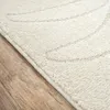 Close-up view of a cream-colored rug with a subtle beige pattern, placed on a wooden floor. Produktbild-Vorschau
