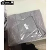 A gray polka dot fabric item, likely a travel organizer, is shown inside clear plastic packaging. Voir les images du produit