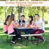 A group of young people are sitting around a picnic table in a park, eating and drinking. Produktbild-Vorschau