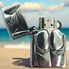 A silver Zippo lighter with a sculpted design of buttocks is placed on a sandy beach with the ocean and sky in the background. Podgląd zdjęcia produktu
