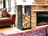 A black metal firewood rack filled with logs sits next to a stone fireplace and a brown leather sofa. Voir les images du produit