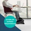 A man sits at a desk with a laptop and a smartphone, using a footrest. Produktbild-Vorschau