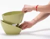 Hands are shown interacting with a two-tiered self-watering planter. Náhled obrázku produktu