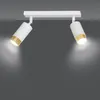 A white ceiling light fixture with two adjustable spotlights, each with a gold accent ring, mounted on a white bar. The lights are illuminated, casting a soft glow. Podgląd zdjęcia produktu