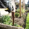 A person is using a sledgehammer to drive a metal post support into the ground in a garden. Produktbild-Vorschau