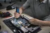 A person is working on a laptop motherboard with a magnifying tool. Voir les images du produit