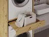 A close-up view of a laundry cabinet with a pull-out shelf holding a laundry basket and a towel, next to a washing machine. Voir les images du produit