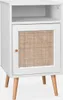 A white bedside table with a rattan door and wooden legs is shown against a white background. Produktbild-Vorschau