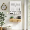 A white wall-mounted cabinet with slatted doors, a small shelf, and two drawers below, decorated with plants, books, and a clock. Podgląd zdjęcia produktu
