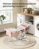 A small, foldable drying rack with clothes and shoes is placed on a rug in a laundry room setting. Produktbild-Vorschau