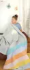 A young girl is wrapped in a colorful striped blanket. Produktbild-Vorschau