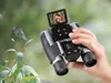 A person is holding binoculars with a small screen displaying a squirrel, in an outdoor, natural setting with foliage. Produktbild-Vorschau