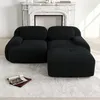 A black sectional sofa is shown in a well-lit room with a fireplace in the background and a rug on the floor. Produktbild-Vorschau
