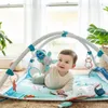 A baby is playing on a colorful ocean-themed playmat with a play gym and toys. Produktbild-Vorschau