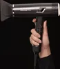 A hand holding a black Rowenta hair dryer against a black background. Podgląd zdjęcia produktu