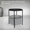 A black side table with a gray fabric bag underneath, displayed in a studio setting with a blurred background vase. Náhled obrázku produktu