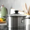 A stainless steel pot with a glass lid is placed on a black induction stovetop in a kitchen setting. Produktbild-Vorschau