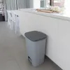 A light gray pedal trash can is placed on a tiled floor next to a white kitchen counter. Náhled obrázku produktu