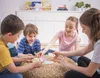 Four children are sitting on the floor playing a card game. Voir les images du produit