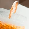 A close-up shot of the lid of a clear plastic food storage container filled with corn flakes. Produktbild-Vorschau