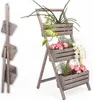 A wooden plant stand with three tiers, filled with various plants and flowers, displayed against a white background. The stand is shown in both an open and a folded state. Anteprima dell’immagine prodotto