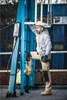 A man in work clothes and a hard hat is climbing a ladder next to a blue industrial structure. Produktbild-Vorschau