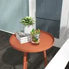 A small orange side table with a plant, books, and a drink on it, placed on a wooden deck next to a blue door. Produktbild-Vorschau