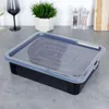 A black cake container with a transparent lid sits on a gray countertop. Náhled obrázku produktu