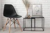 A black chair and a small side table with a framed picture and decorative items against a white brick wall. Anteprima dell’immagine prodotto