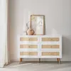 A white dresser with rattan drawer fronts, decorated with two vases and a framed picture. Produktbild-Vorschau