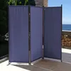 A three-panel blue fabric room divider is set up on an outdoor patio with a view of the ocean in the background. Produktbild-Vorschau