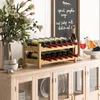 A wooden wine rack filled with wine bottles sits on a cabinet, with a vase of flowers and a chalkboard menu in the background. Podgląd zdjęcia produktu