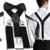 A man wearing a white shirt and black pants, with black suspenders and a black bow tie attached. Produktbild-Vorschau