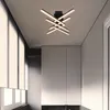 A modern ceiling light fixture with multiple intersecting bars, illuminating a room with a minimalist aesthetic. Náhled obrázku produktu
