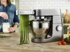A person is using a Kenwood kitchen mixer with a pasta attachment to make fettuccine. Produktbild-Vorschau