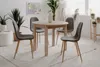 A round dining table with four gray chairs in a bright, modern room. Voir les images du produit