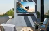 An outdoor patio with a TV and soundbar mounted on a wall, overlooking a city view. Produktbild-Vorschau