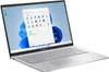 A silver ASUS laptop is shown from a slightly elevated side angle, open with the screen displaying the Windows 11 interface. Produktbild-Vorschau
